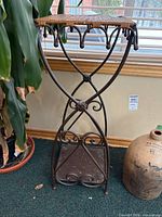 Full view of plant stand showing wicker top and scrollwork legs