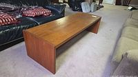 Angled view of rectangular brown wood veneer coffee table on carpet between sofas