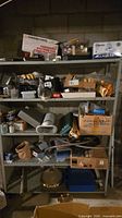 Full shelving unit with assorted boxed and loose plumbing, electrical and hardware items