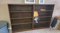 Front view of both brown wood veneer bookcases side by side