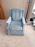 Front view of light blue wingback armchair showing tufted back, seat cushion, skirted base