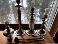 Group shot of four candlesticks, snuffer and wick trimmer on windowsill