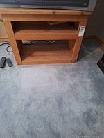 Front view of small solid wood TV stand showing two open shelves