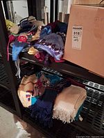 Overview of lot on shelving showing folded sweaters, scarves, hats