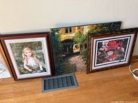 Wide shot of three artworks leaning against wall