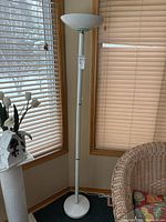 Full view of white torchiere floor lamp in corner