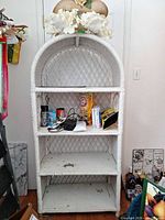Front view of white wicker etagere showing four shelves and arched top