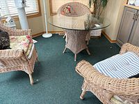 wicker table with glass top and two chairs in room