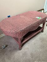 Full view of pink wicker coffee table with lower shelf