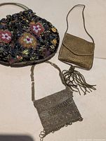 Three purses laid out: beaded evening purse, gold brocade change purse, Birks seed-bead coin purse