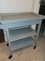 Front view of light grey painted three-tier trolley on casters