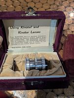 Lens in open velvet case showing instruction card