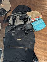 Assorted bags including Adrienne Vittadini backpack, black briefcase bag, Derek Alexander backpack, and three small cosmetic bags