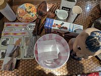 Assorted items on table including fork and spoon, plates, containers, bowls, coasters, mug, utensils