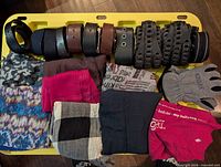 Rolled belts, folded scarves and gloves on yellow tote lid