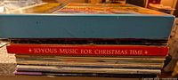 Side view of stacked vinyl records showing multiple album spines including Joyous Music for Christmas Time, total height suggests 21 records