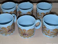 Five matching light blue floral mugs front view