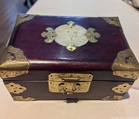 Closed rosewood jewelry box showing jade medallion and brass corners