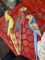All three wooden parrots displayed on red bin lid
