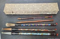 Five brushes and patterned case arranged on dark surface