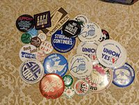 Group of pins spread on carpet showing union and Solidarity slogans