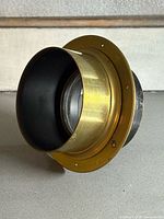 Front angled view of brass lens showing mounting flange and interior hood