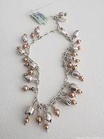 Full view of silver-tone Pilgrim charm bracelet with faux pearl and metal drops, tag visible