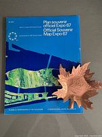 Cover of Official Souvenir Map Expo 67 with copper maple-leaf ashtray on top