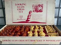 Open box showing two coloured sets of chessmen and printed lid