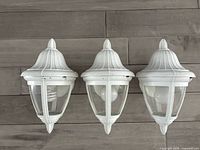 Front view of three matching white outdoor wall lanterns