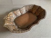 Top view showing oval shape, scalloped rim, floral repousse and hammered center
