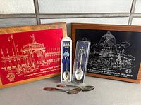 Group view: two CNE plaques, two packaged souvenir spoons, three loose spoons