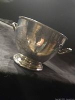 Side view of silver plated pedestal bowl showing engraved lines and handles