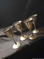 Four tarnished silver-plated goblets lined up