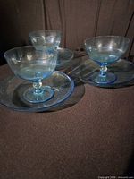 Three blue glass dessert cup and plate sets grouped