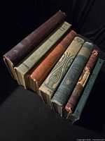 Seven vintage books stacked showing spines