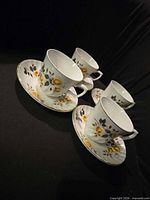 Four cup and saucer sets displayed on black background