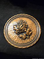 Top view of round copper plate with raised floral design