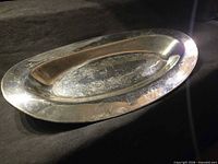 Top view of oval silver-plated tray showing scroll engraving and reflective surface