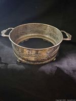 Side view showing overall shape, handles, feet, and tarnish