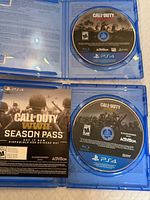 Open PS4 cases showing two Call of Duty game discs and WWII Season Pass insert