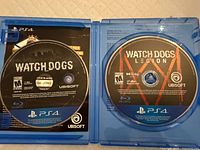 Open PS4 case showing Watch Dogs disc on left and Watch Dogs: Legion disc on right
