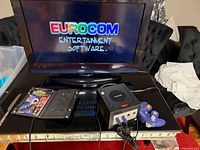 Console, controller, cords shown connected to TV displaying Eurocom screen