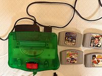 Top view of translucent green Nintendo 64 console with attached cable and four game cartridges