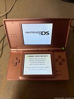 Console open, powered on displaying Nintendo DS logo and health & safety screen