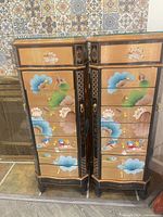 Front view of the two matching lacquered jewelry chests showing drawer fronts and decorative painting