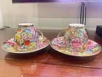 Two teacups placed upside down on matching saucers showing full floral exterior