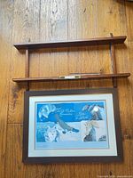 Framed blue print mounted below matching wall shelf