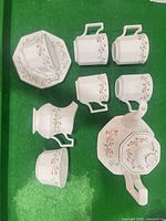 Overhead view of full tea set: teapot, sugar bowl, creamer, six mugs