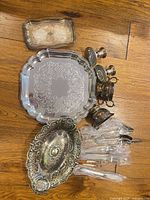 Group shot of all items on floor showing trays, centerpiece bowl, small vessels, candlesticks and wrapped flatware